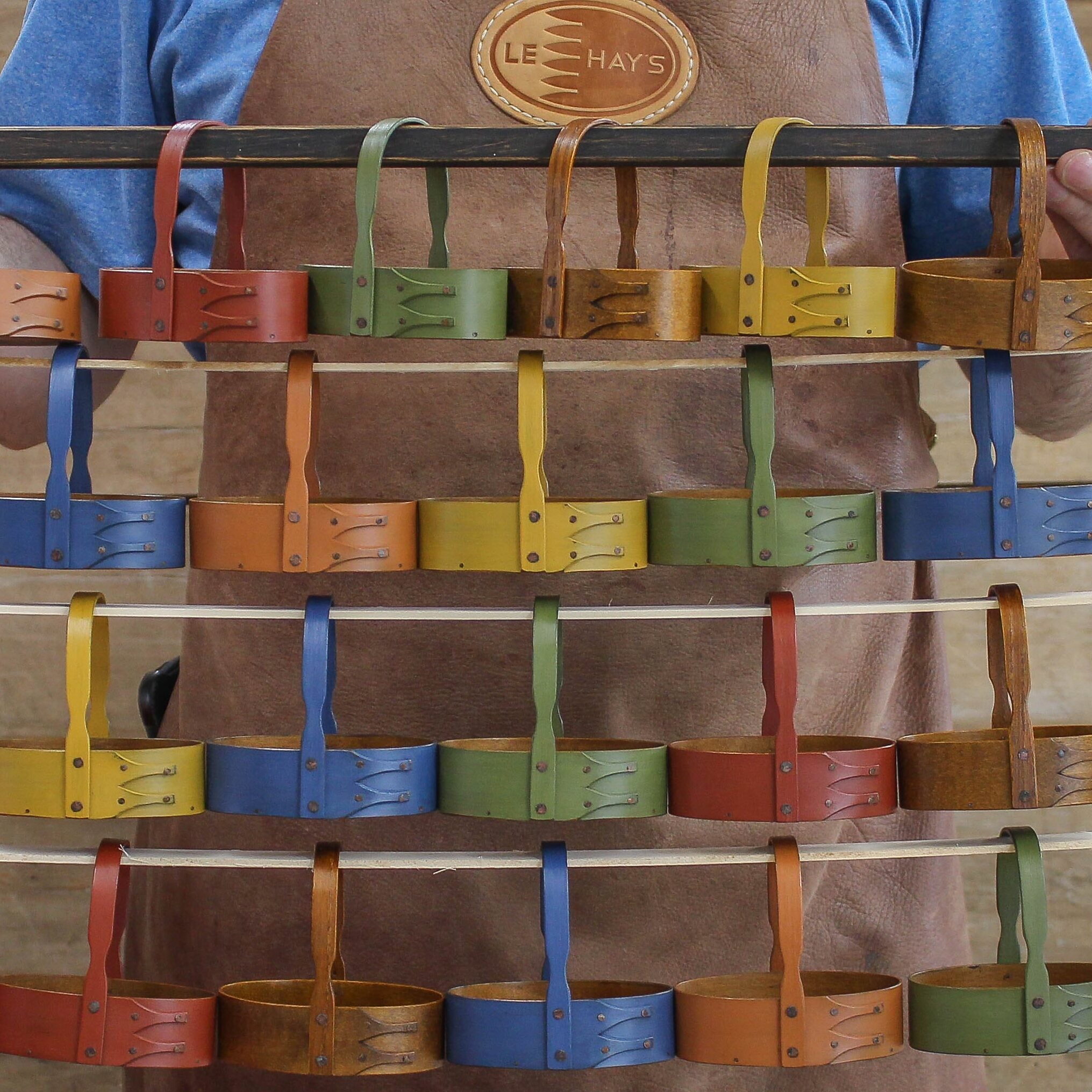 Handcrafted wooden shaker carriers with fixed handles, displayed in vibrant colors, made in Maine for holiday ornament use.