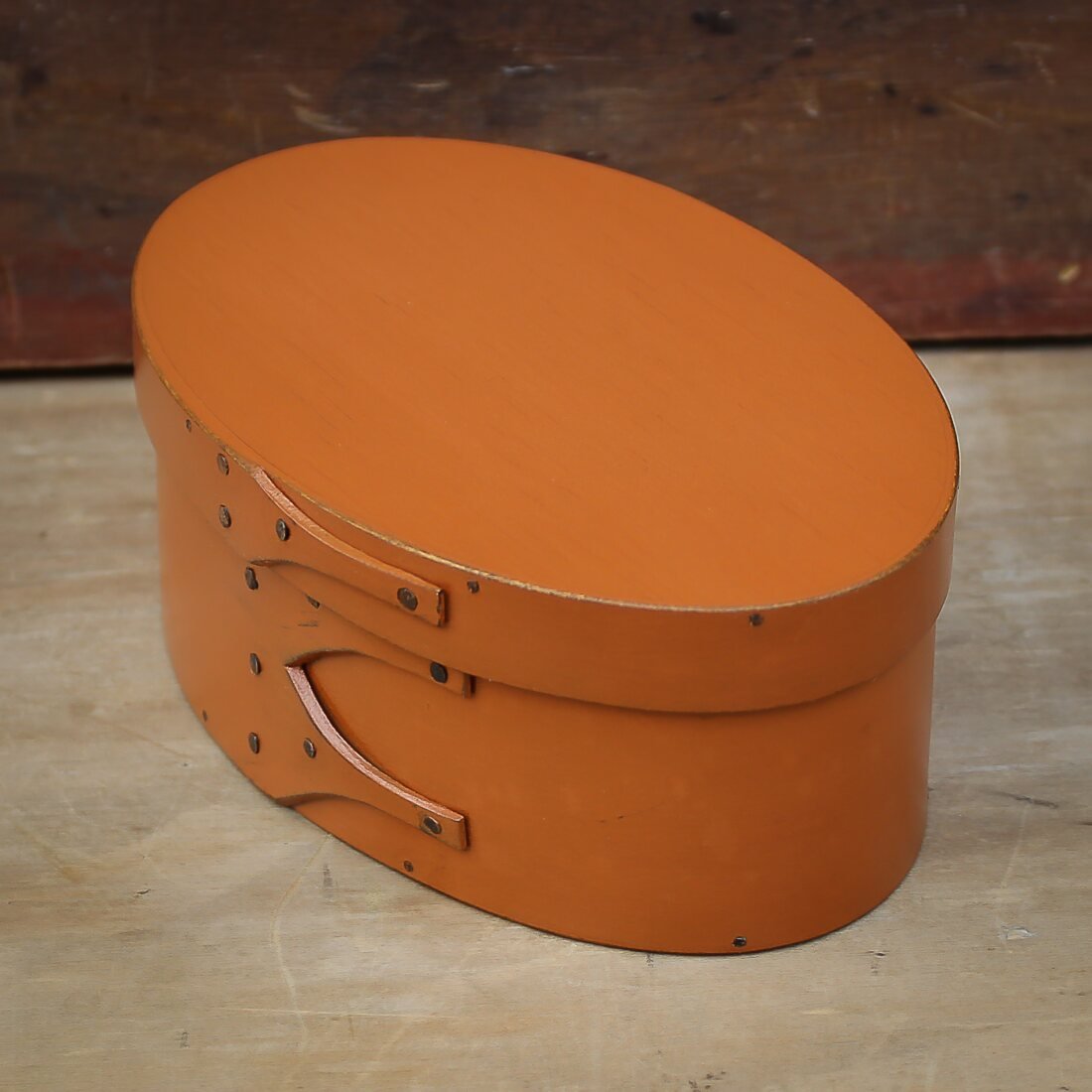 Handcrafted wooden oval shaker box in orange, perfect for sewing and needlework, made in Maine.