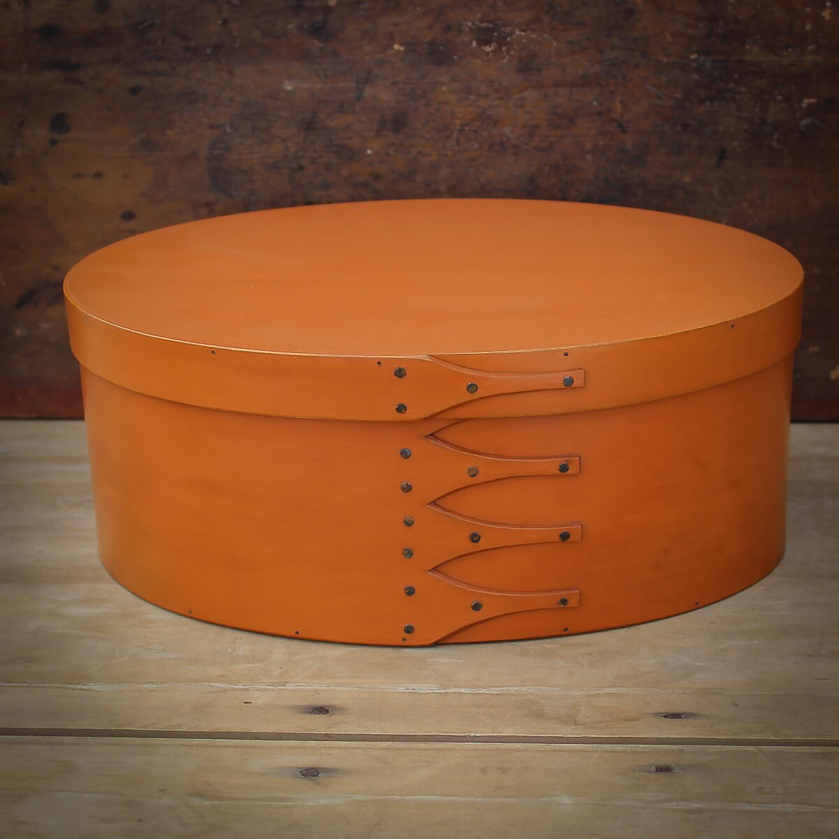 Handcrafted wooden shaker box from Maine, ideal for sewing and needlework, featuring an elegant oval design in pumpkin color.