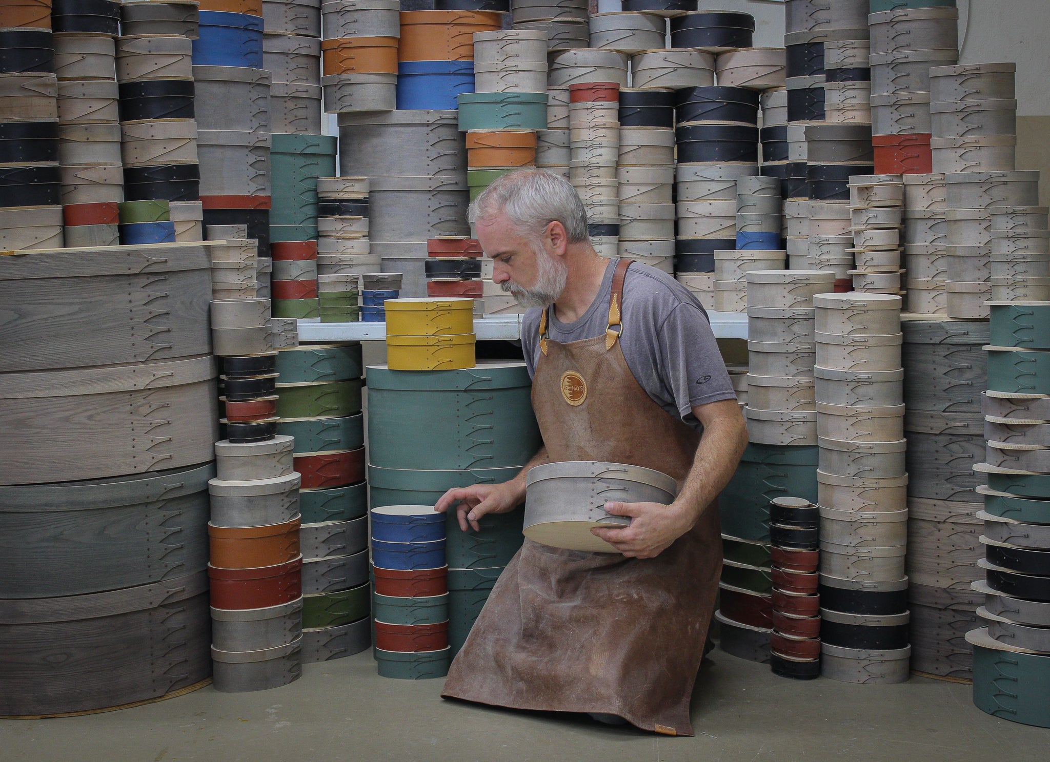 Rob kneeling in a room walled floor-to-ceiling with painted boxes