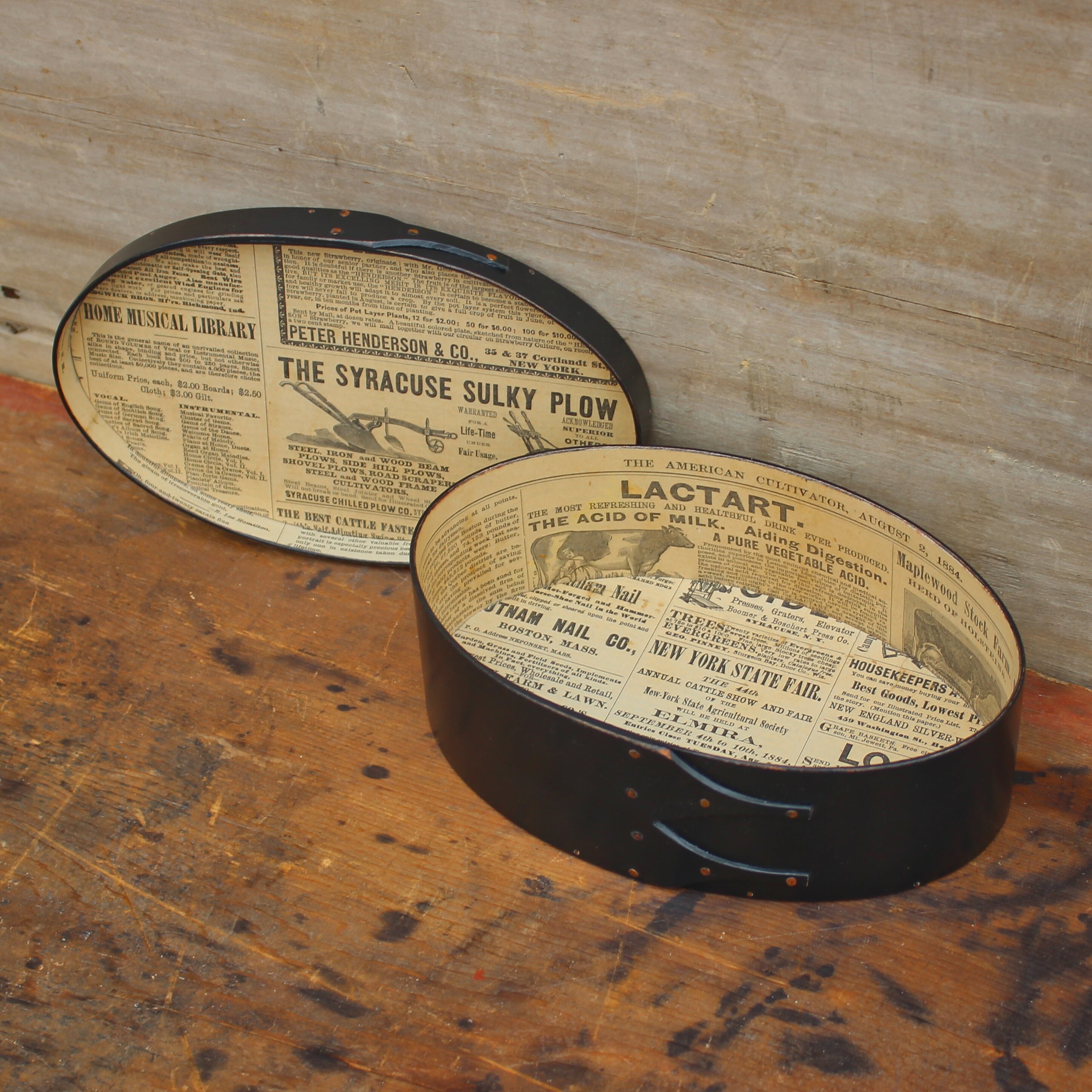 A paper-lined oval box in black milk paint, lid off