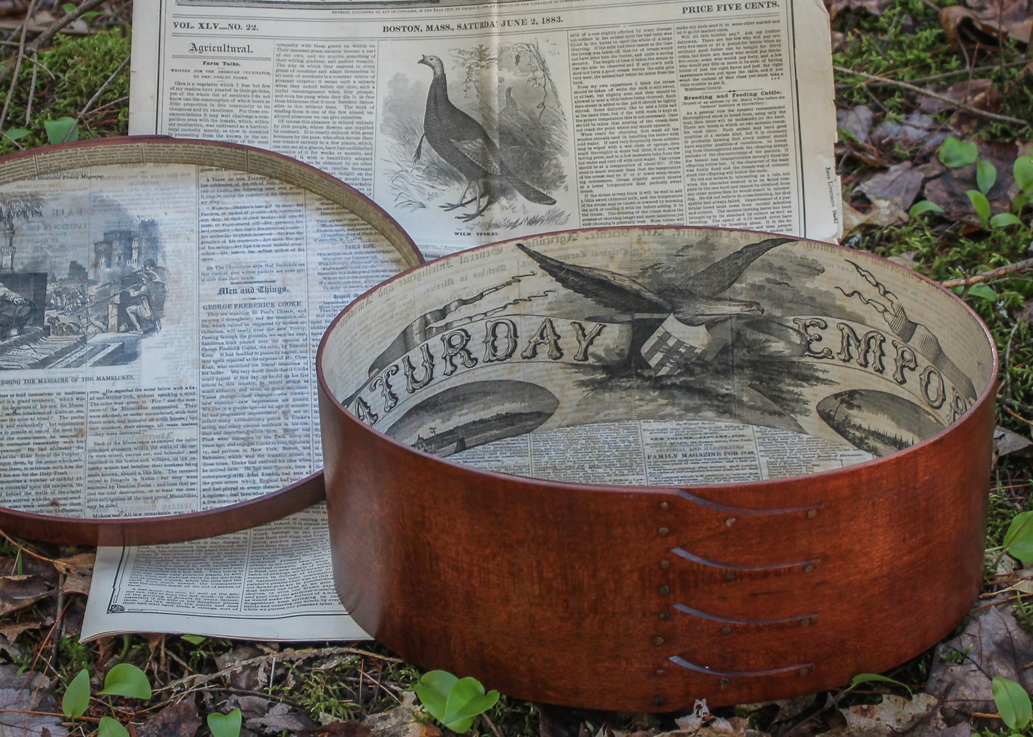 A paper-lined oval box staged with an antique newspaper