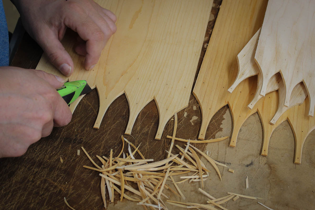 Hand-trimming the swallowtail fingers with a knife, shavings on the bench